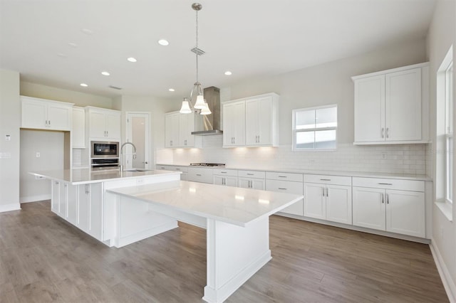 10320 Longmeadow Ave, Parrish, FL 34219 - kitchen featuring wall chimney range hood, appliances with stainless steel finishes, a sink, recessed lighting, and a spacious island
