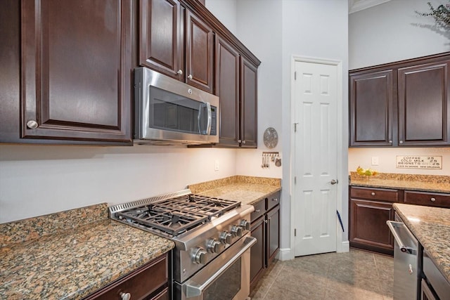 610 Winterside Dr, Apollo Beach, FL 33572 - kitchen featuring appliances with stainless steel finishes, dark brown cabinetry, stone countertops, light tile patterned flooring, and crown molding