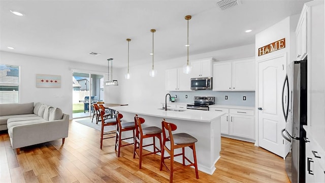 9293 Rally Spring Loop, Wesley Chapel, FL 33545 - kitchen featuring appliances with stainless steel finishes, open floor plan, light wood-style flooring, a kitchen bar, and a sink