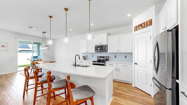9293 Rally Spring Loop, Wesley Chapel, FL 33545 - kitchen featuring stainless steel appliances, a sink, light wood-style flooring, a kitchen bar, and light countertops