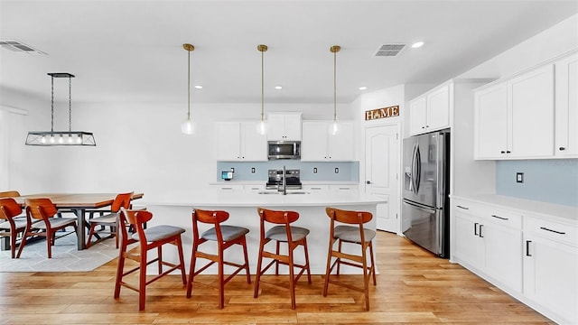 9293 Rally Spring Loop, Wesley Chapel, FL 33545 - kitchen featuring stainless steel appliances, light wood-style floors, a sink, light countertops, and recessed lighting
