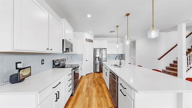 9293 Rally Spring Loop, Wesley Chapel, FL 33545 - kitchen with stainless steel appliances, a sink, light wood-style flooring, decorative backsplash, and light countertops