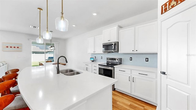 9293 Rally Spring Loop, Wesley Chapel, FL 33545 - kitchen with appliances with stainless steel finishes, a sink, light wood finished floors, a breakfast bar, and backsplash