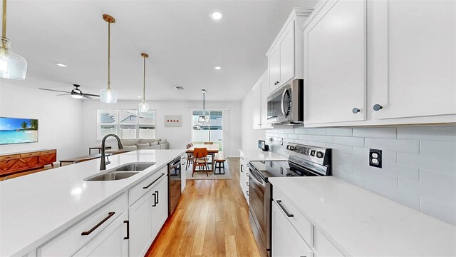 9293 Rally Spring Loop, Wesley Chapel, FL 33545 - kitchen with stainless steel appliances, a sink, light countertops, light wood-style flooring, and recessed lighting