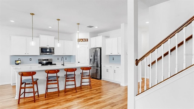 9293 Rally Spring Loop, Wesley Chapel, FL 33545 - kitchen featuring stainless steel appliances, a breakfast bar area, light wood-style flooring, light countertops, and recessed lighting
