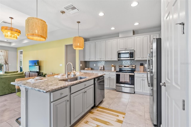30801 Parrot Reef Ct, Wesley Chapel, FL 33545 - kitchen featuring stainless steel appliances, a sink, decorative backsplash, open floor plan, and an island with sink