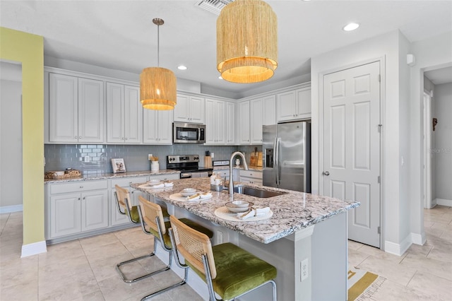 30801 Parrot Reef Ct, Wesley Chapel, FL 33545 - kitchen with stainless steel appliances, a sink, baseboards, backsplash, and a center island with sink