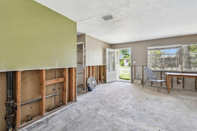 123 14th Ave, Indian Rocks Beach, FL 33785 - unfurnished living room featuring a textured ceiling and unfinished concrete flooring