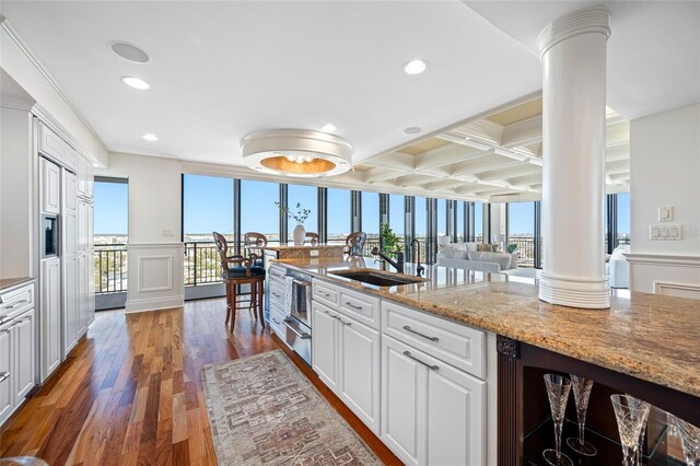 7600 Bayshore Dr Unit 1201A, Treasure Island, FL 33706 - kitchen with decorative columns, a sink, coffered ceiling, wood finished floors, and white cabinetry