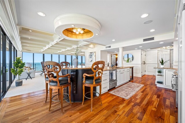 7600 Bayshore Dr Unit 1201A, Treasure Island, FL 33706 - kitchen featuring white cabinetry, dishwashing machine, wood finished floors, a breakfast bar, and recessed lighting