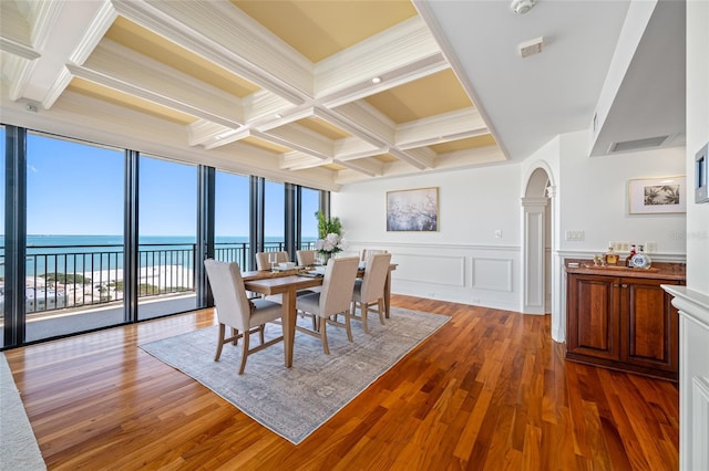 7600 Bayshore Dr Unit 1201A, Treasure Island, FL 33706 - dining area featuring arched walkways, coffered ceiling, beam ceiling, wood finished floors, and a water view