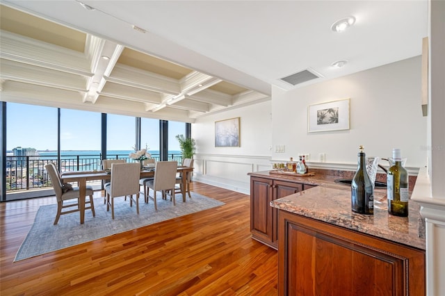 7600 Bayshore Dr Unit 1201A, Treasure Island, FL 33706 - dining space with beamed ceiling, coffered ceiling, light wood-style floors, a water view, and a decorative wall