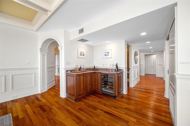7600 Bayshore Dr Unit 1201A, Treasure Island, FL 33706 - indoor wet bar featuring beverage cooler, ornate columns, dark wood finished floors, arched walkways, and a decorative wall