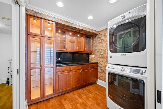 7600 Bayshore Dr Unit 1201A, Treasure Island, FL 33706 - washroom featuring stacked washer and clothes dryer, light wood finished floors, baseboards, crown molding, and recessed lighting