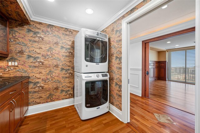7600 Bayshore Dr Unit 1201A, Treasure Island, FL 33706 - laundry area with stacked washer and clothes dryer, light wood-style floors, wallpapered walls, ornamental molding, and a wainscoted wall