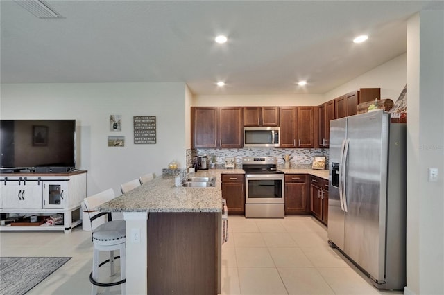1398 Crescent Hoop Way, Wesley Chapel, FL 33543 - kitchen featuring appliances with stainless steel finishes, a sink, a peninsula, a kitchen bar, and backsplash