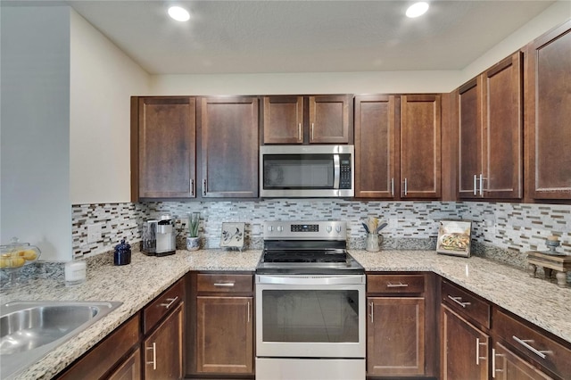 1398 Crescent Hoop Way, Wesley Chapel, FL 33543 - kitchen featuring appliances with stainless steel finishes, backsplash, light stone countertops, a sink, and recessed lighting
