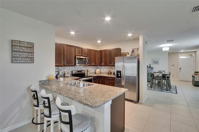 1398 Crescent Hoop Way, Wesley Chapel, FL 33543 - kitchen featuring appliances with stainless steel finishes, a peninsula, backsplash, a sink, and a breakfast bar
