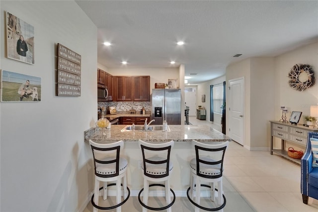 1398 Crescent Hoop Way, Wesley Chapel, FL 33543 - kitchen featuring stainless steel appliances, a sink, backsplash, a peninsula, and light stone countertops