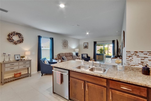 1398 Crescent Hoop Way, Wesley Chapel, FL 33543 - kitchen with stainless steel dishwasher, a sink, open floor plan, brown cabinets, and light stone counters