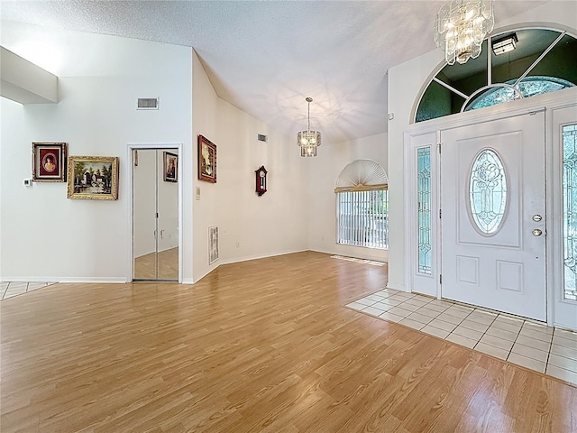 2973 Spring Oak Ct, Palm Harbor, FL 34684 - entrance foyer featuring a chandelier, light wood finished floors, vaulted ceiling, baseboards, and a textured ceiling