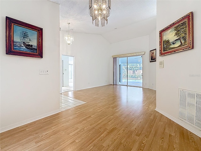 2973 Spring Oak Ct, Palm Harbor, FL 34684 - empty room featuring a chandelier, vaulted ceiling, light wood-style floors, baseboards, and a textured ceiling