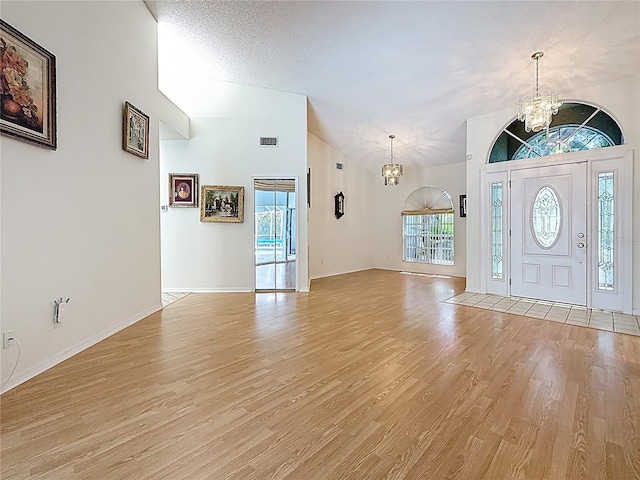 2973 Spring Oak Ct, Palm Harbor, FL 34684 - foyer entrance featuring a chandelier, vaulted ceiling, light wood-type flooring, and baseboards