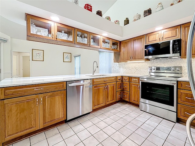2973 Spring Oak Ct, Palm Harbor, FL 34684 - kitchen with appliances with stainless steel finishes, a sink, brown cabinetry, light countertops, and backsplash