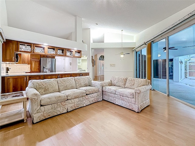 2973 Spring Oak Ct, Palm Harbor, FL 34684 - living area featuring ceiling fan, light wood-style flooring, a textured ceiling, high vaulted ceiling, and arched walkways