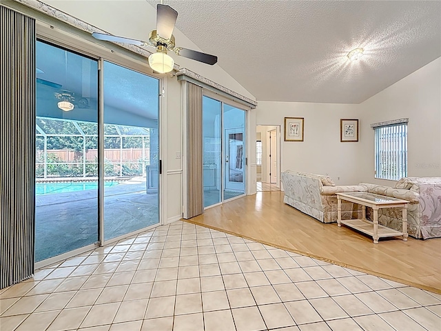 2973 Spring Oak Ct, Palm Harbor, FL 34684 - living room featuring vaulted ceiling, a ceiling fan, light tile patterned floors, a textured ceiling, and plenty of natural light