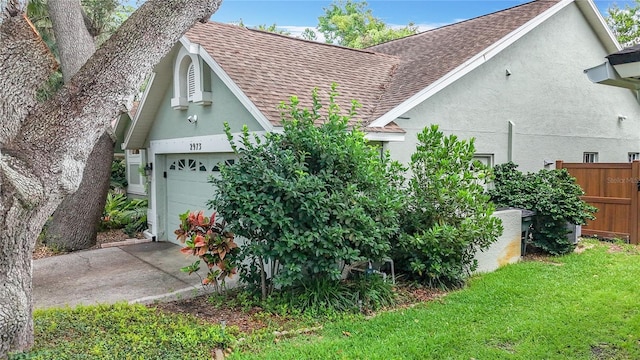 2973 Spring Oak Ct, Palm Harbor, FL 34684 - view of side of home featuring a shingled roof, stucco siding, an attached garage, and driveway