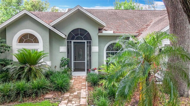 2973 Spring Oak Ct, Palm Harbor, FL 34684 - view of exterior entry featuring roof with shingles and stucco siding