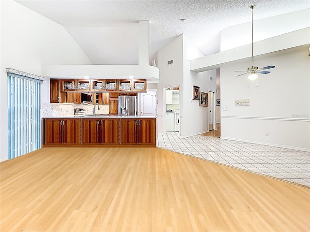 2973 Spring Oak Ct, Palm Harbor, FL 34684 - unfurnished living room with independent washer and dryer, high vaulted ceiling, a ceiling fan, and light wood finished floors