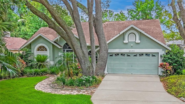 2973 Spring Oak Ct, Palm Harbor, FL 34684 - view of front of property with roof with shingles, stucco siding, concrete driveway, and an attached garage