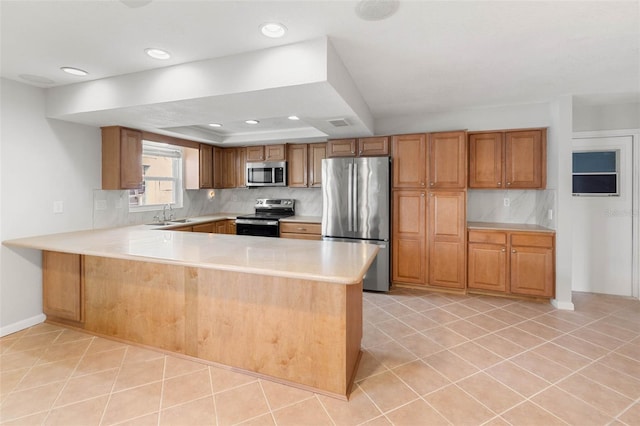 4299 Bellaire Dr, Hernando Beach, FL 34607 - kitchen with stainless steel appliances, light countertops, a peninsula, tasteful backsplash, and brown cabinets