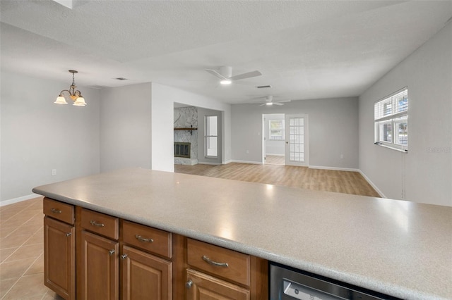 4299 Bellaire Dr, Hernando Beach, FL 34607 - kitchen featuring dishwasher, brown cabinetry, pendant lighting, a stone fireplace, and open floor plan