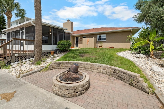 4299 Bellaire Dr, Hernando Beach, FL 34607 - rear view of house featuring a sunroom, a chimney, a lawn, a patio area, and a fire pit