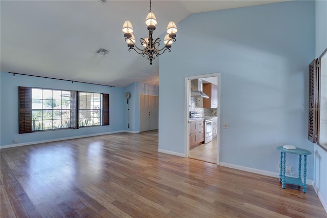 8521 Caitlin Ct, Hudson, FL 34667 - unfurnished living room featuring a chandelier, vaulted ceiling, light wood-style floors, and baseboards