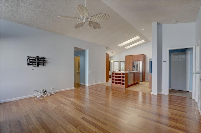 8521 Caitlin Ct, Hudson, FL 34667 - unfurnished living room with vaulted ceiling, light wood-type flooring, a skylight, a textured ceiling, and a ceiling fan