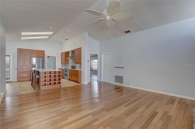 8521 Caitlin Ct, Hudson, FL 34667 - unfurnished living room featuring light wood-style floors, a sink, ceiling fan, high vaulted ceiling, and a textured ceiling