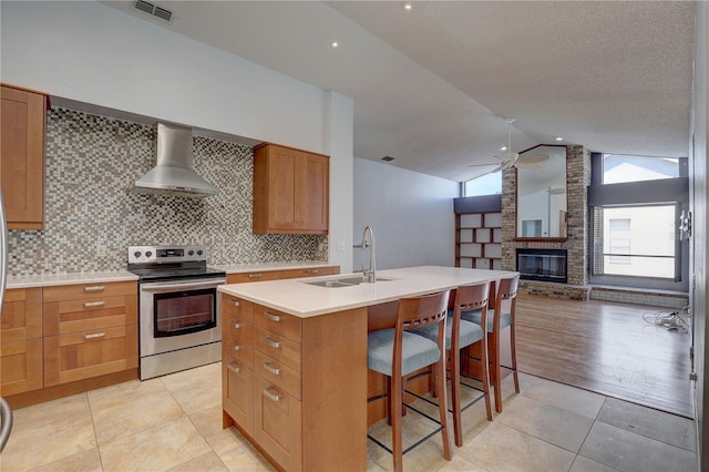 8521 Caitlin Ct, Hudson, FL 34667 - kitchen with stainless steel electric range, wall chimney range hood, a sink, a ceiling fan, and a fireplace