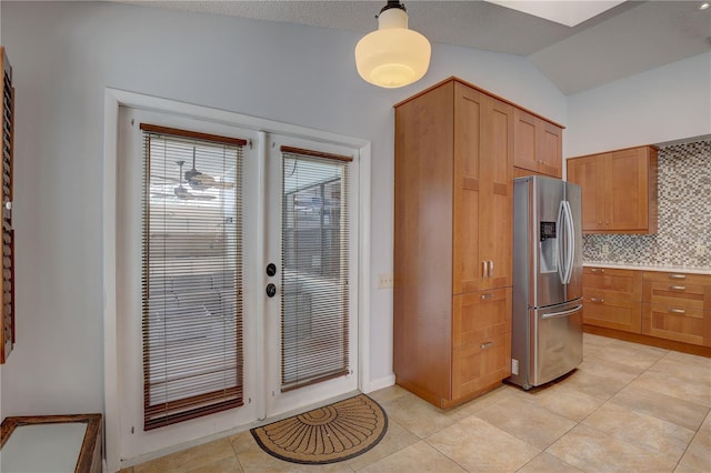 8521 Caitlin Ct, Hudson, FL 34667 - kitchen featuring stainless steel fridge, backsplash, light tile patterned floors, lofted ceiling, and light countertops