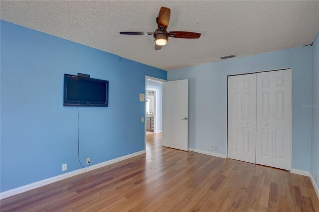 8521 Caitlin Ct, Hudson, FL 34667 - unfurnished bedroom featuring wood finished floors, a textured ceiling, baseboards, a closet, and ceiling fan