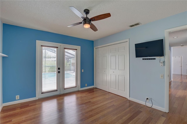 8521 Caitlin Ct, Hudson, FL 34667 - unfurnished bedroom with french doors, access to outside, wood finished floors, a textured ceiling, and baseboards