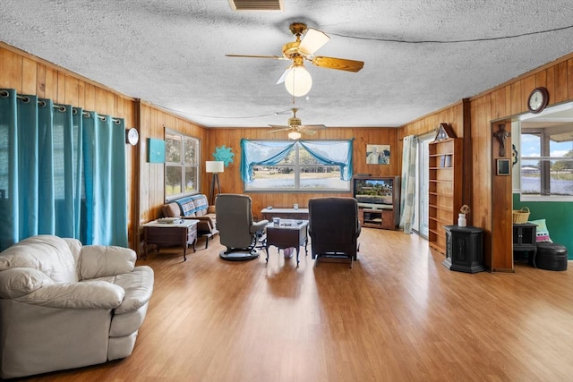 1226 S Telephone Point Rd, Inverness, FL 34450 - living area with wood finished floors, wood walls, a ceiling fan, a wood stove, and a textured ceiling