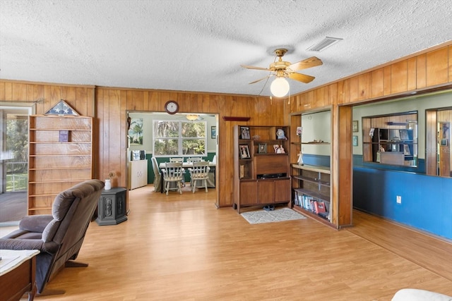 1226 S Telephone Point Rd, Inverness, FL 34450 - home office with a textured ceiling, wood walls, wood finished floors, ceiling fan, and a wood stove