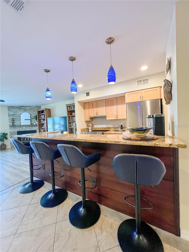 659 Garland Cir, Indian Rocks Beach, FL 33785 - kitchen featuring freestanding refrigerator, light brown cabinets, light stone counters, a breakfast bar, and recessed lighting