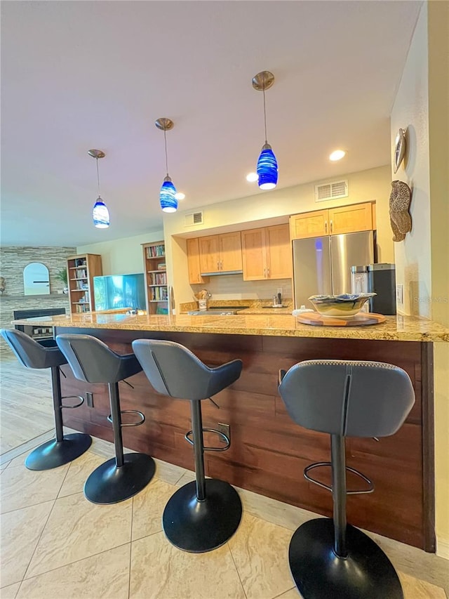 659 Garland Cir, Indian Rocks Beach, FL 33785 - kitchen featuring freestanding refrigerator, light brown cabinets, decorative light fixtures, a kitchen breakfast bar, and light stone countertops