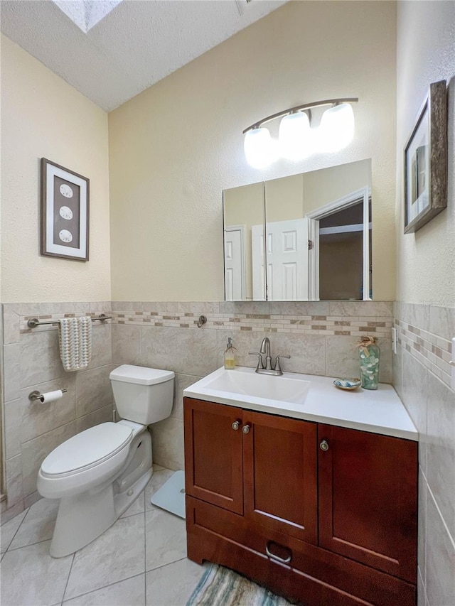 659 Garland Cir, Indian Rocks Beach, FL 33785 - bathroom with tile walls, toilet, vanity, a textured ceiling, and wainscoting