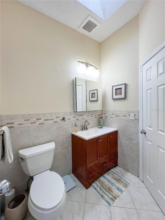 659 Garland Cir, Indian Rocks Beach, FL 33785 - bathroom with tile walls, vanity, toilet, a wainscoted wall, and a textured ceiling